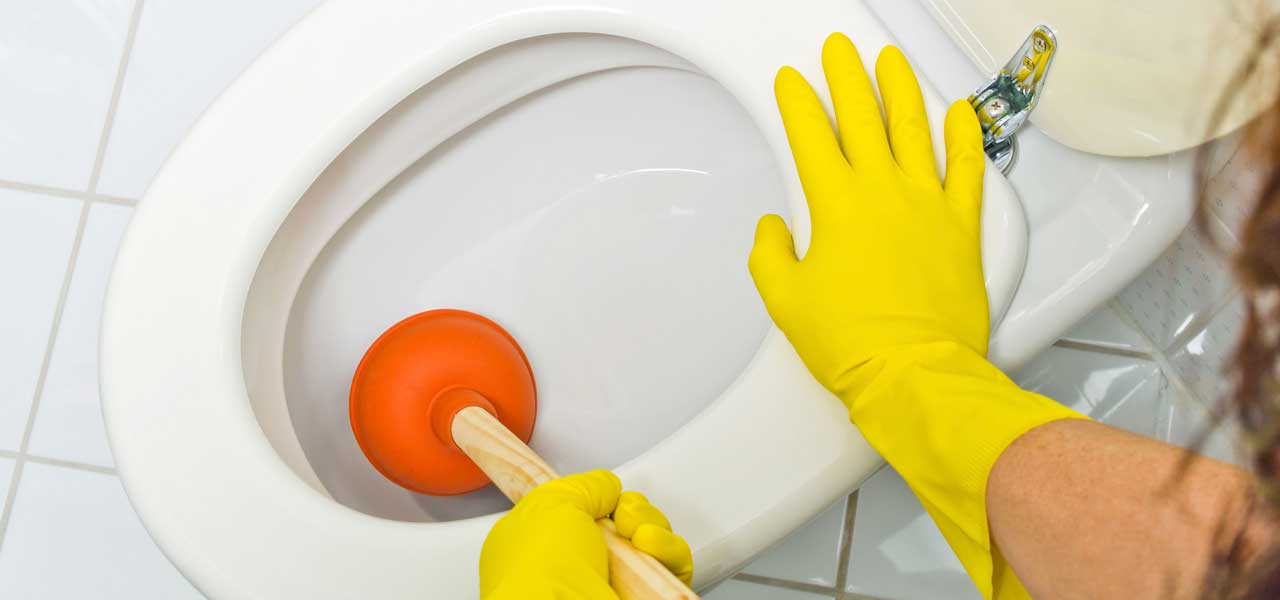 Close Up of Homeowner Trying to Unclog Toilet with Plunger